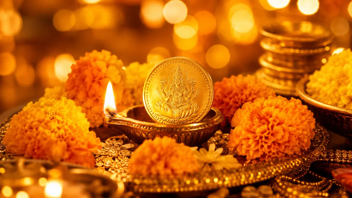 Gold Lakshmi coin with a diya and marigold flowers for the festival season